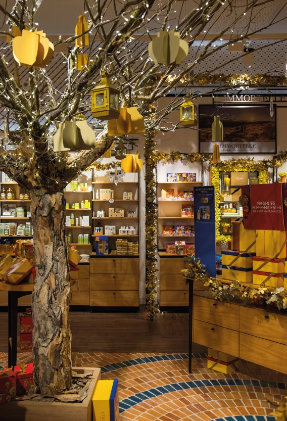 Árvore cenográfica e ornamentos dourados na ambientação natalina de uma loja L’Occitane.